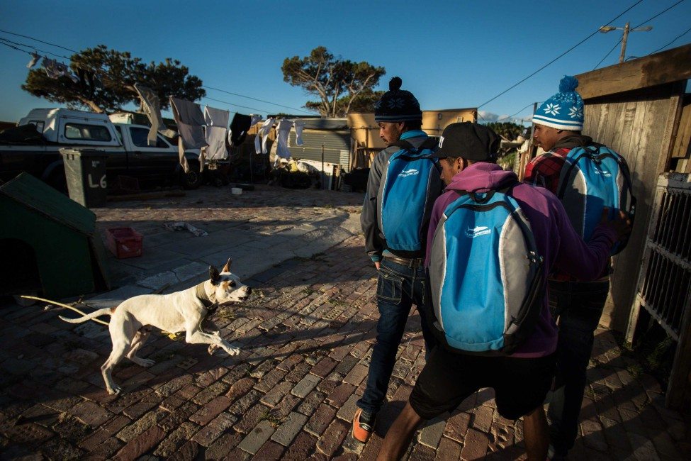 Many of the Shark Spotters live in crowded and impoverished townships outside Cape Town. Funded by the local municipality, local businesses and the Save Our Seas Foundation, the programme provides much-needed jobs and income to under-served communities. Its members wear their branded backpacks and shirts with pride in the communities.